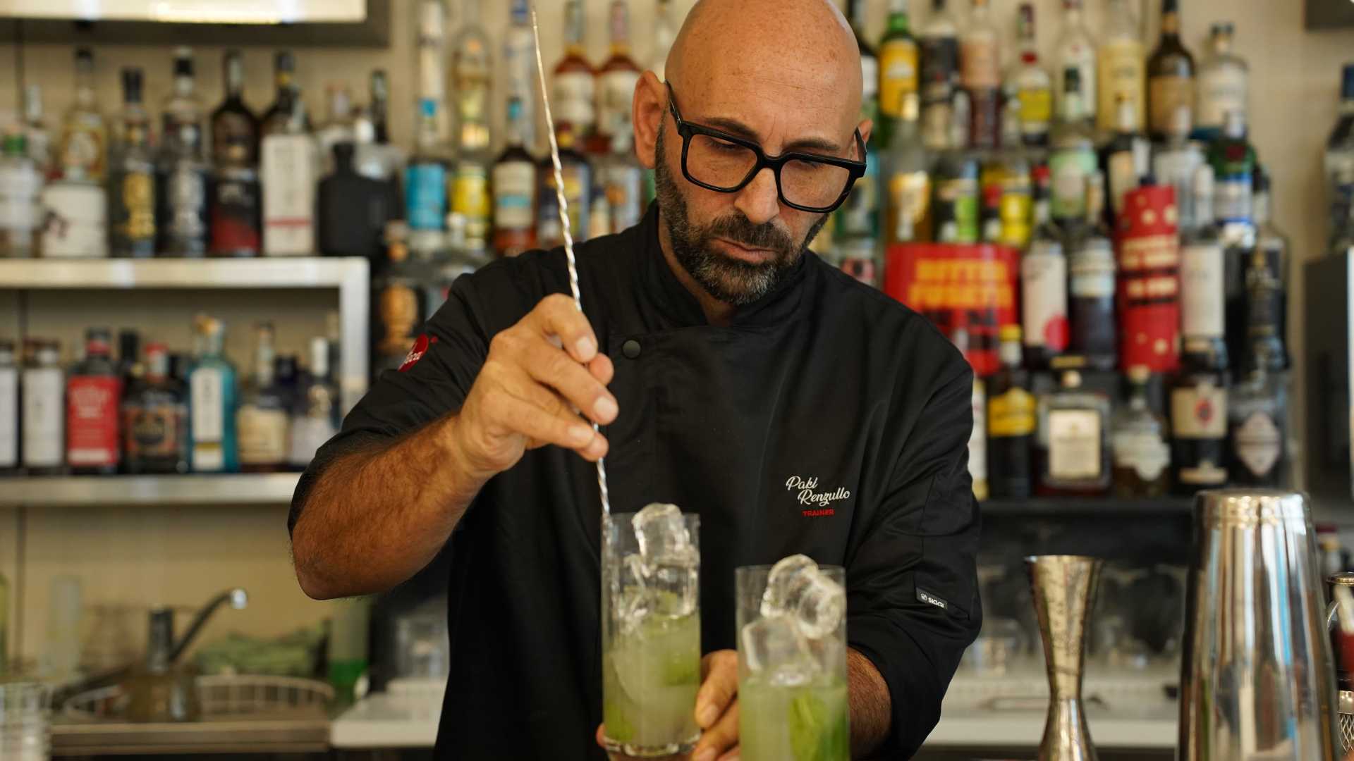 Trainer al banco mentre miscela con precisione, tecnica stir e controllo del ghiaccio, formazione per cocktail classici come Old Fashioned. | Ad Horeca