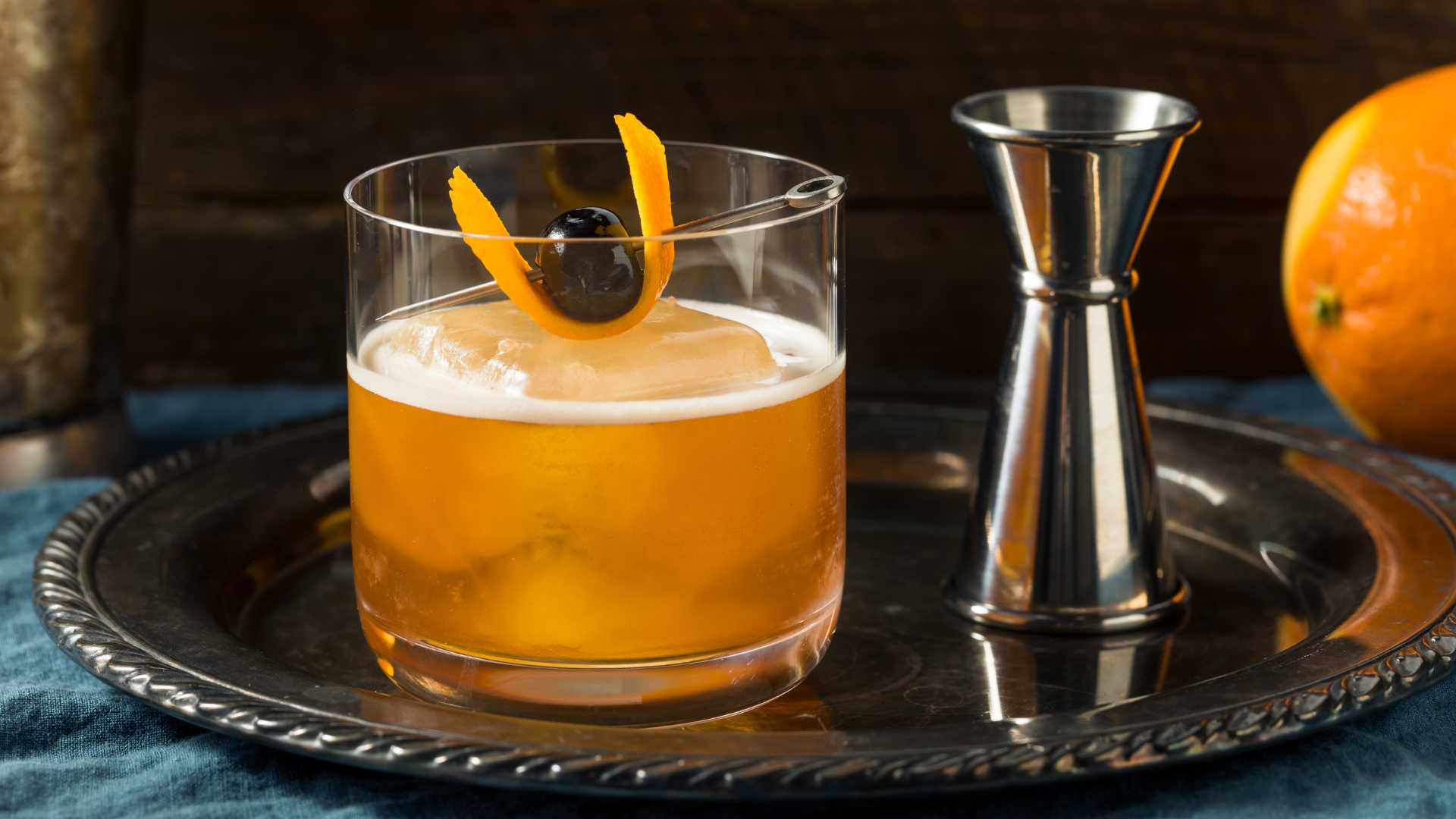 Old Fashioned cocktail in bicchiere lowball con ghiaccio grande, scorza d’arancia e ciliegia, foto copertina del blog. | Ad Horeca